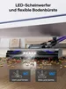 A vacuum cleaner head with LED lights is cleaning debris from a wooden floor. Produktbild-Vorschau