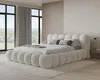 A modern bedroom with a large, plush bed and large windows overlooking a green landscape. Voir les images du produit