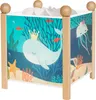 A square-shaped night light with a colorful ocean-themed illustration on its sides, featuring a whale, jellyfish, and underwater scenery. It has wooden posts and spherical wooden accents on top. Produktbild-Vorschau