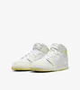 A pair of white and cream Nike Air Jordan 1 Mid sneakers with yellow soles, presented against a white background. Podgląd zdjęcia produktu