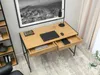 A modern desk with drawers open, showing books and a laptop, in a room with a large framed picture on the wall and a bookshelf. Náhled obrázku produktu