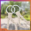 Close-up of two silver rings with beige ropes attached, against a blurred green and light gray background. Náhled obrázku produktu