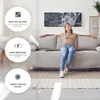 A woman relaxing on a sofa in a living room with a modern heater on the wall. Produktbild-Vorschau