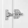 A close-up view of a cabinet hinge attached to white surfaces. Produktbild-Vorschau