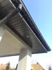 A low-angle view of a building's soffit and gutter system under a clear blue sky. Produktbild-Vorschau