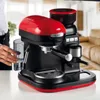 A person's hand is holding a glass next to a red and black espresso machine. Produktbild-Vorschau