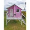 A pink playhouse for children is set up in a grassy outdoor area. Produktbild-Vorschau