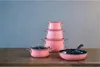 A set of pink cookware is arranged on a wooden table against a textured gray background. Anteprima dell’immagine prodotto