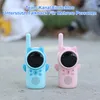 Two children's walkie-talkies, one blue and one pink, are placed on a textured surface, possibly concrete or stone. Produktbild-Vorschau