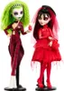 Two Monster High dolls, one with green hair and a red pinstripe suit, the other with black hair and a red dress, are displayed on stands against a white background. Voir les images du produit