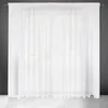A white sheer curtain hanging in front of a window. Voir les images du produit
