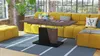 A modern living room with a yellow sectional sofa, a coffee table, and a rug. Produktbild-Vorschau
