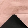 A close-up view of a pink shaggy rug, showing the texture of the pile and the black backing with a patterned grip. Voir les images du produit