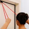 A person is using red resistance bands attached to a door frame for exercise. Produktbild-Vorschau
