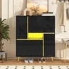 A modern black shoe cabinet with gold accents and a bright yellow interior compartment, placed in a home entryway with a plant and artwork. Podgląd zdjęcia produktu