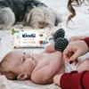A baby is lying on a bed with a pack of baby wipes next to it. Two dogs are in the background. Podgląd zdjęcia produktu