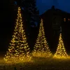 Three illuminated Christmas trees in a yard at night with a house in the background. Produktbild-Vorschau