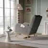 A cozy living room scene featuring a gray teddy bear fabric rocking chair next to a window with sheer curtains, a floor lamp, and a small side table with books and a vase. Produktbild-Vorschau