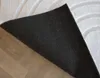 The underside of a rug is shown, with the rug partially lifted to reveal the flooring underneath. Produktbild-Vorschau