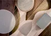 A close-up overhead view of several sanding discs and a sanding block arranged on a wooden surface. Produktbild-Vorschau
