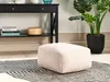 A beige cord pouf sits on a rug in front of a black console table with books and a plant in a pot. Náhled obrázku produktu