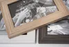Three photo frames are arranged diagonally on a white background. The top frame is a light wood color and shows a black and white photo of two people toasting with champagne glasses. The bottom left frame is white and appears empty. The bottom right frame  Náhled obrázku produktu