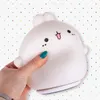 A hand holding a white bunny-shaped night light against a colorful polka dot background. Produktbild-Vorschau