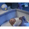 A baby is lying in a crib next to a night light and stuffed animals. Produktbild-Vorschau