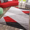 A modern living room with a red sofa, a geometric rug, and a green ottoman. Voir les images du produit