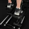 A close-up shot of a person's feet on an elliptical machine. Produktbild-Vorschau