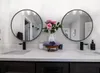 A bathroom vanity with two round mirrors, sinks, faucets, and decorative items. Anteprima dell’immagine prodotto