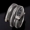 A close-up studio shot of a silver, snake-shaped bracelet watch with a black face and diamond accents, set against a black background. Náhled obrázku produktu