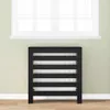 A black radiator cover with horizontal slats is shown in front of a window with white blinds. The cover is placed on a wooden floor against a light green wall. Anteprima dell’immagine prodotto