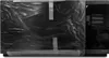 A black Samsung microwave oven is covered in plastic wrap and secured with tape. Produktbild-Vorschau