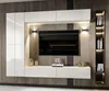A modern living room entertainment unit with a wall-mounted TV, white cabinets, and decorative items. Produktbild-Vorschau