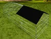 A wire cage with a black cover sits on a green lawn. Voir les images du produit