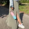 A person holding a water bottle while walking outdoors. Produktbild-Vorschau