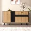 A wooden sideboard with black accents is displayed in a room with a painting on the wall and a plant in the background. Voir les images du produit