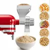 A red KitchenAid stand mixer attachment for grinding grains, with various grains shown in circular insets. Produktbild-Vorschau