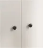 A close-up view of two doors of a white cabinet or wardrobe, each with a black round knob. Produktbild-Vorschau