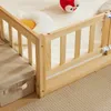 A close-up view of a wooden children's bed frame with a storage box next to it. Produktbild-Vorschau
