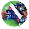 A hand is opening an advent calendar with a colorful, illustrated design of houses and a night sky. Produktbild-Vorschau