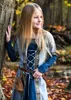 A young girl in a medieval-style dress stands in a forest during autumn. Produktbild-Vorschau