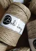 A close-up shot of several spools of Bobbiny macrame cord in a beige color with subtle gold threads. Podgląd zdjęcia produktu