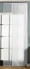 A white panel curtain with a laser-cut pattern hangs in front of a window with a grid pattern. The curtain is on a track system. Produktbild-Vorschau