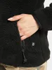 A close-up of a person's hand reaching into the pocket of a black fleece jacket. Produktbild-Vorschau