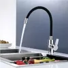 A kitchen faucet with a flexible black spout is shown with water running into a sink containing some vegetables. Náhľad obrázku produktu