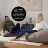A man and a woman are relaxing on large beanbag chairs in a living room setting. Anteprima dell’immagine prodotto