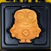 A waffle in the shape of a Minion character is shown in a waffle maker. Produktbild-Vorschau