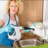 A woman is cleaning a kitchen faucet with a handheld steam cleaner. Produktbild-Vorschau